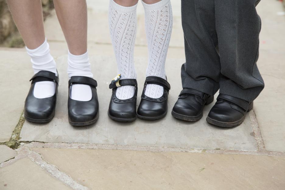 Three children's feet in new school shoes.