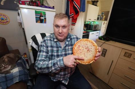 Man holding a cheese pizza, his home overrun with rats.