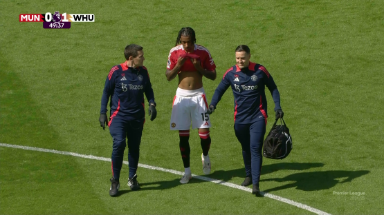 Soccer player escorted off the field by two medical staff.