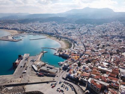 Aerial view of Heraklion, Crete, showing the city's harbor, coastline, and surrounding buildings.