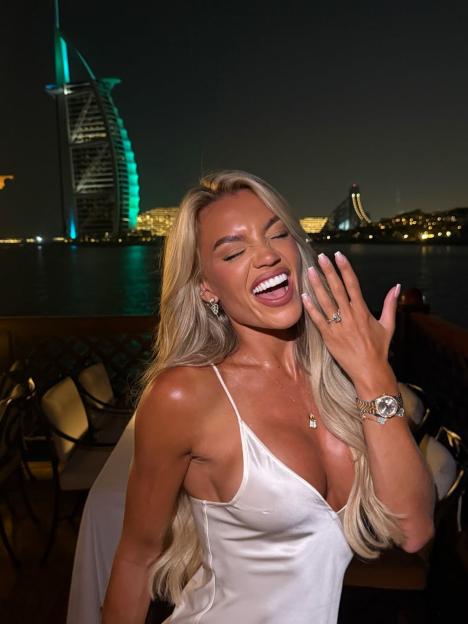 Molly Smith celebrating her engagement, showing her ring, with Dubai's Burj Al Arab in the background.