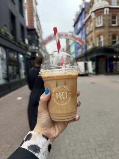 A hand holding a Pret a Manger iced coffee.