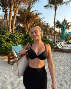 Woman in black bikini and skirt on a beach.