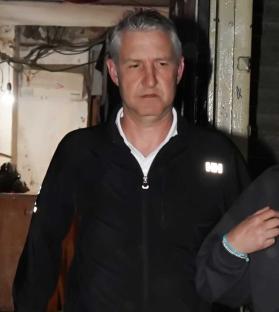 A man in a black zip-up jacket leaving a lawyers office.
