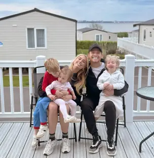 Family of five sitting on chairs outdoors.