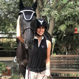 Woman in riding helmet standing with a black horse.