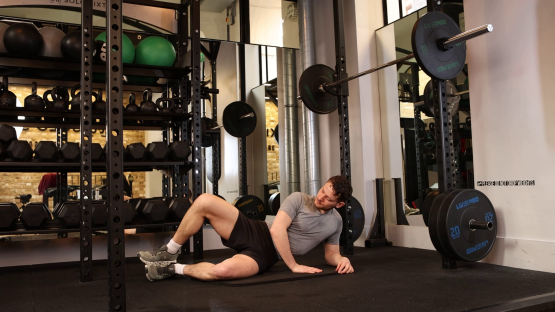 Man performing a glute exercise in a gym.