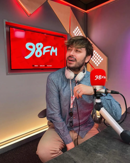 Man sitting at a 98FM radio station microphone.