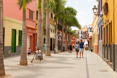 A paved street lined with colorful buildings and palm trees in Puerto de la Cruz, Tenerife.