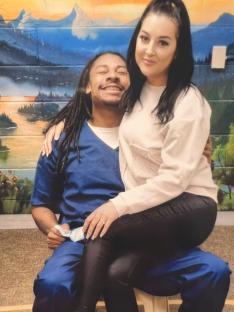 A woman sitting on a man's lap in front of a mural.