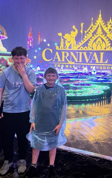 Alix Dawson, 13, and Cole Dawson, 10, standing in front of a Carnival sign.