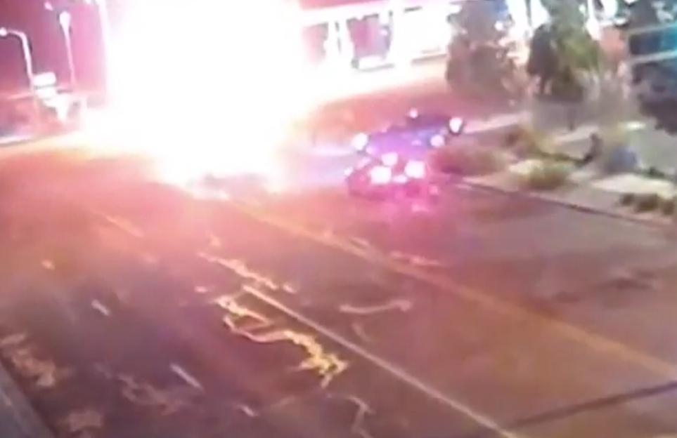 Police pulling a victim from a burning vehicle after a crash.