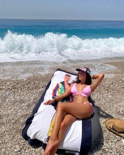 Woman in pink bikini relaxing on beach towel.