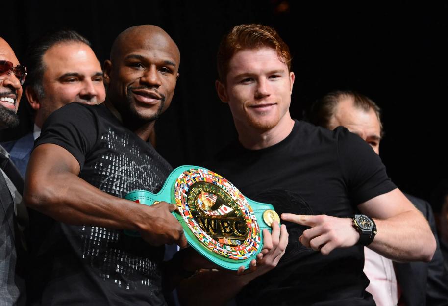 Floyd Mayweather Jr. and Canelo Alvarez holding a WBC super welterweight championship belt.