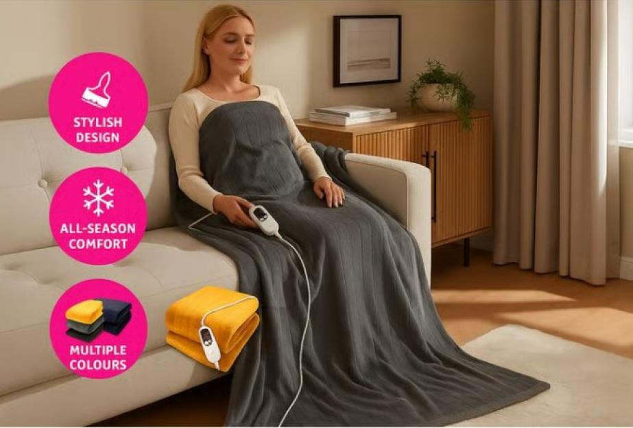 A woman on a sofa covered by a gray heated blanket.