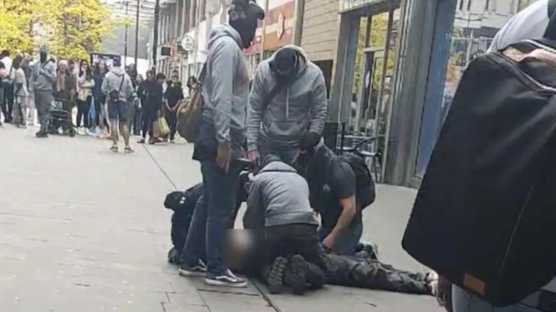People restraining a person on the ground.
