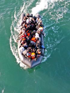 Overhead view of a crowded migrant dinghy in the English Channel.
