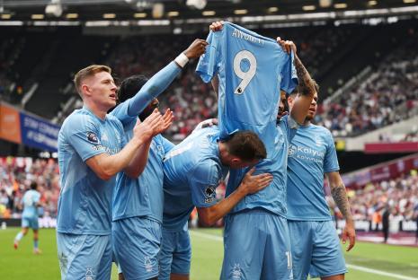 Nottingham Forest players celebrating a goal by holding up a teammate's jersey.
