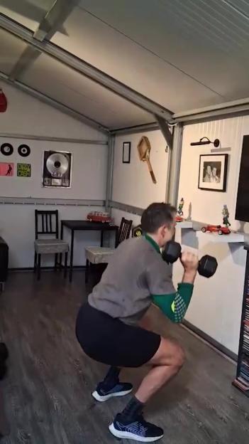 Ronnie O'Sullivan squats with dumbbells in his home gym.