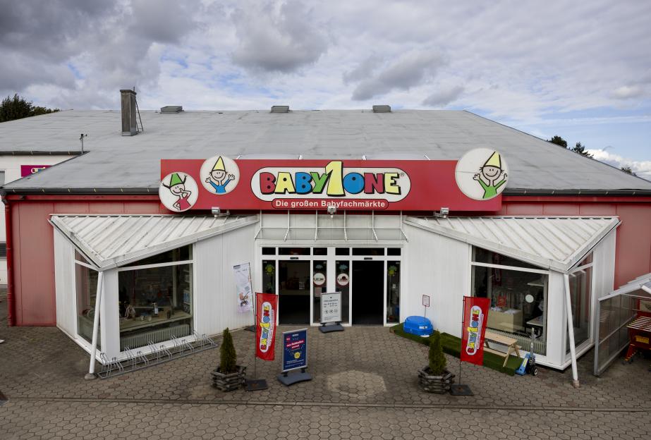Exterior view of a Baby One store with a prominent red sign and gnome-like cartoon figures above the entrance.