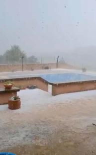 Hailstorm covering a pool and patio area.