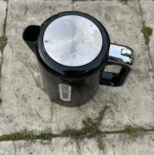 Black electric kettle on a stone surface.