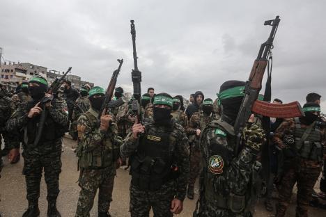 Hamas fighters carrying rifles at a hostage handover in Gaza.