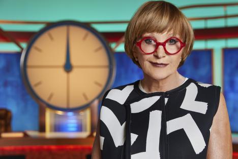 Anne Robinson in a black and white patterned top and red glasses.