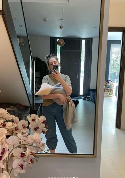 Katherine Ryan holding her baby while taking a mirror selfie.