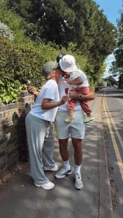 Tommy Fury, Molly Mae Hague, and their child sharing a kiss while holding ice pops.