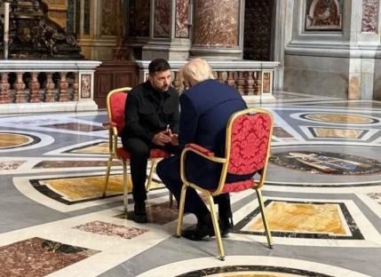 Two men seated in chairs, engaged in conversation.