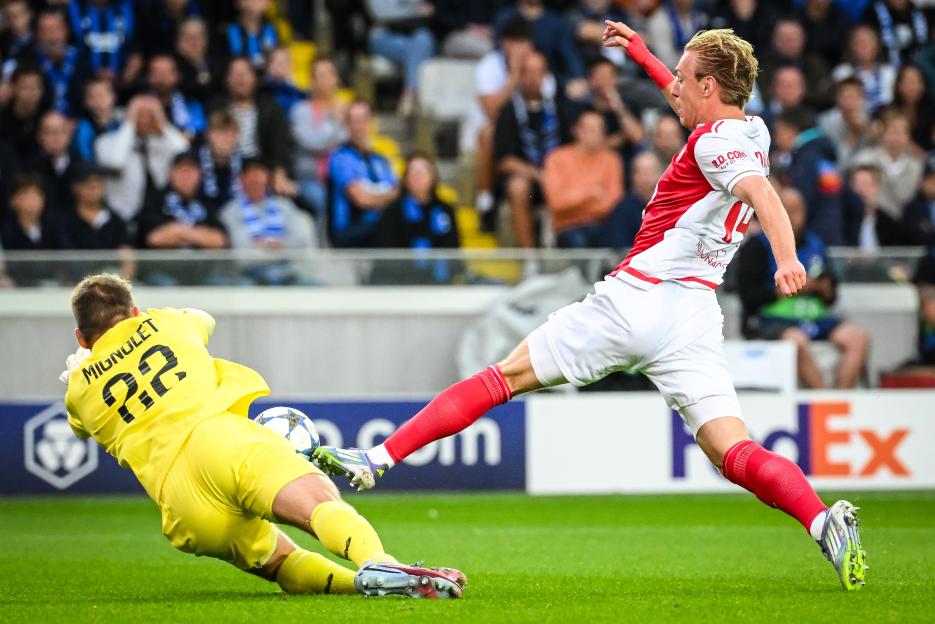 Simon Mignolet of Brugge attempting to save a shot from Mika Biereth of AS Monaco during a football match.