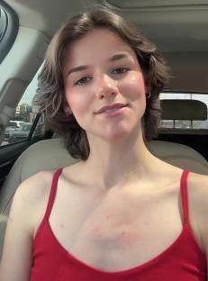 Woman in a red tank top sitting in a car.