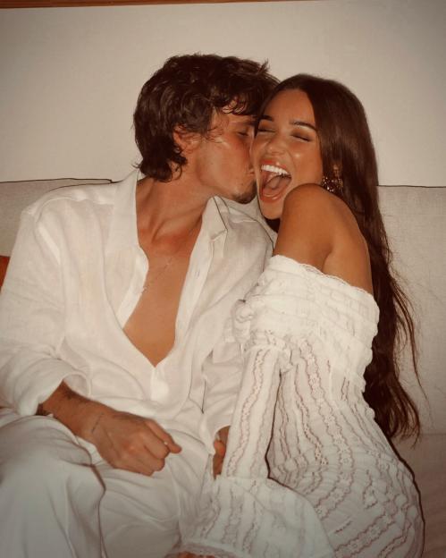 Jackie Apostel laughing as Cruz Beckham kisses her cheek.