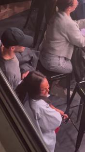 Ruben Dias and Maya Jama cuddling and kissing while watching a football match.