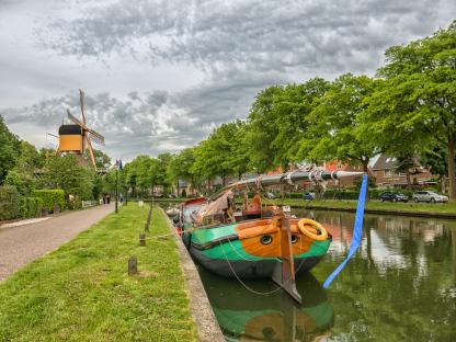 Boat moored by a canal in the Netherlands, with a windmill in the background.