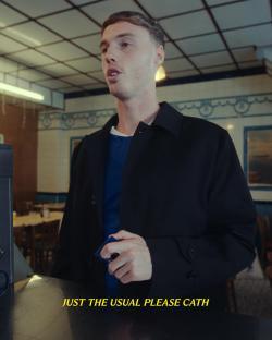 Man in a black coat paying at a counter.