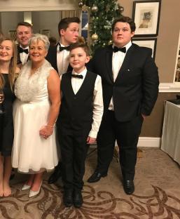 A woman and her four sons dressed in formal attire.