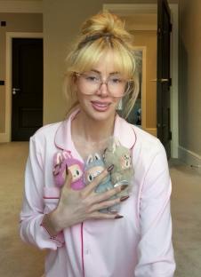 Woman in pajamas holding three small plush toys.