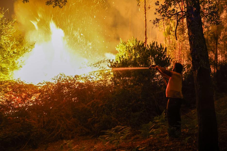 A person fighting a large forest fire at night.
