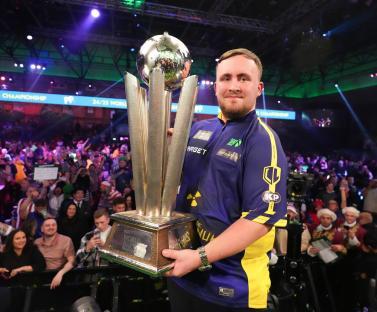 Luke Littler holding the World Darts Championship trophy.