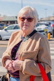 Woman in tan coat and sunglasses in Scunthorpe, Lincolnshire.