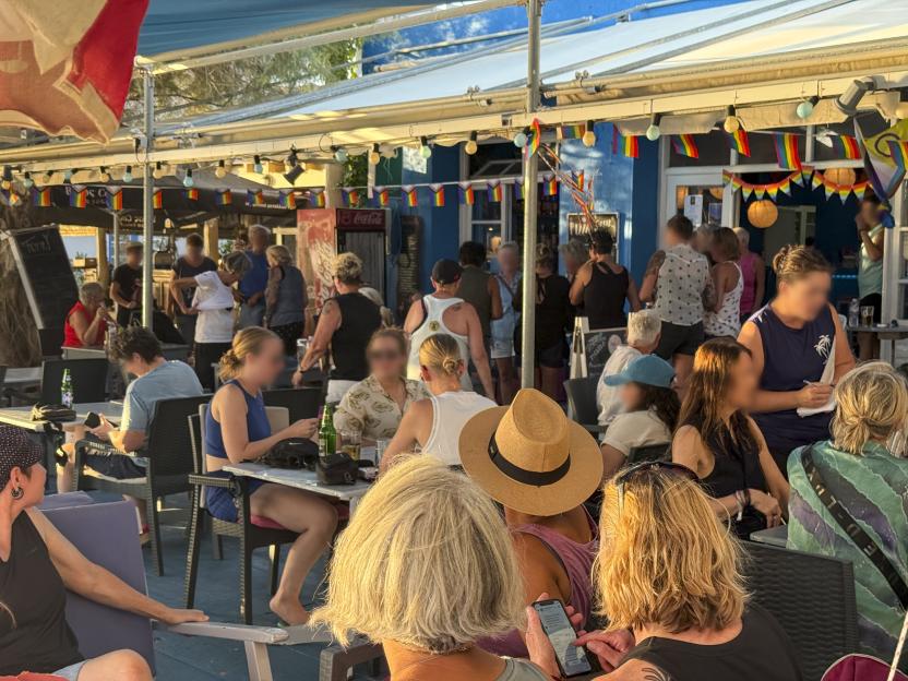 People gathered at the Flamingo bar in Eresos, Lesbos, decorated with rainbow flags for a lesbian festival.