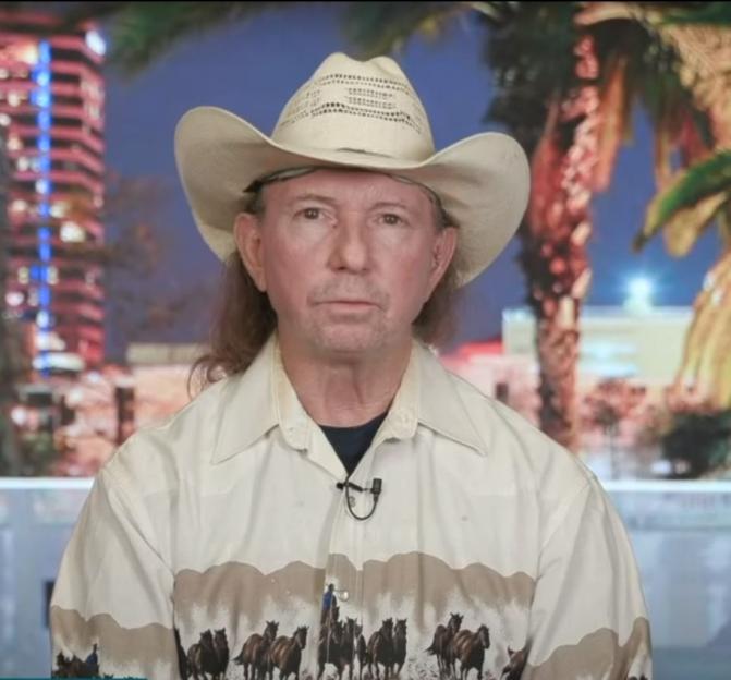 A man in a cowboy hat on a television interview.