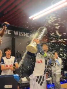 Tottenham Hotspur players celebrating with champagne in the locker room.