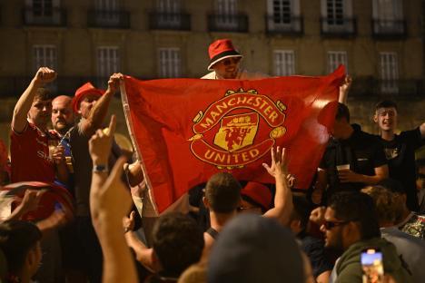 Manchester United fans holding a large team flag.
