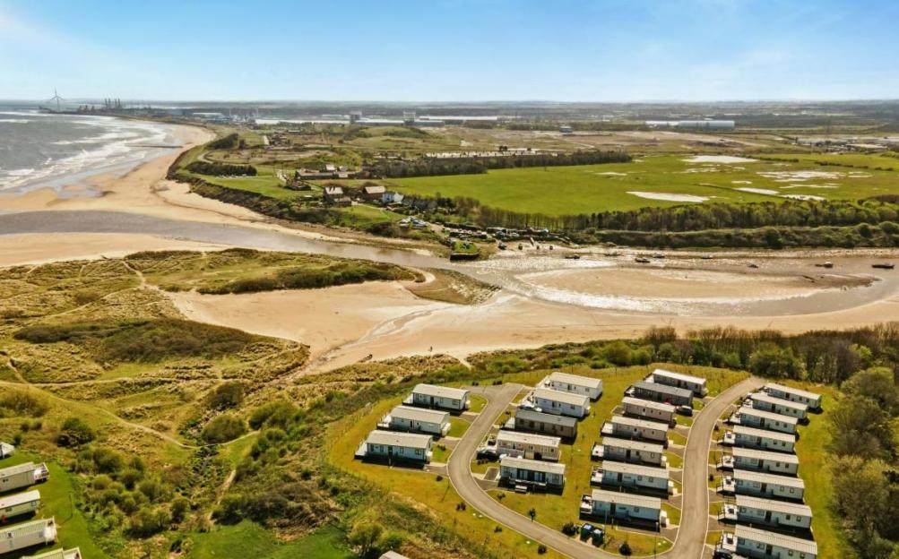 Aerial view of Sandy Bay, Northumberland, showing a caravan park and coastline.