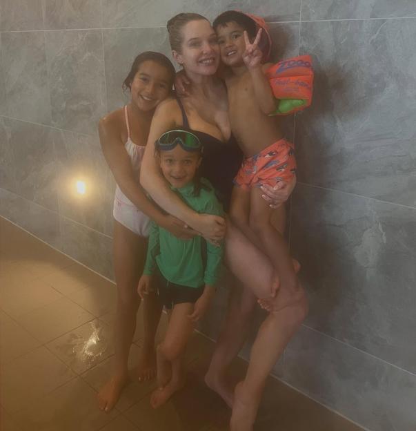 Woman with three children at a pool.