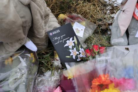 Floral tributes and a memorial card at a memorial site.