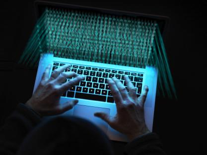 Hacker using laptop to attack software.